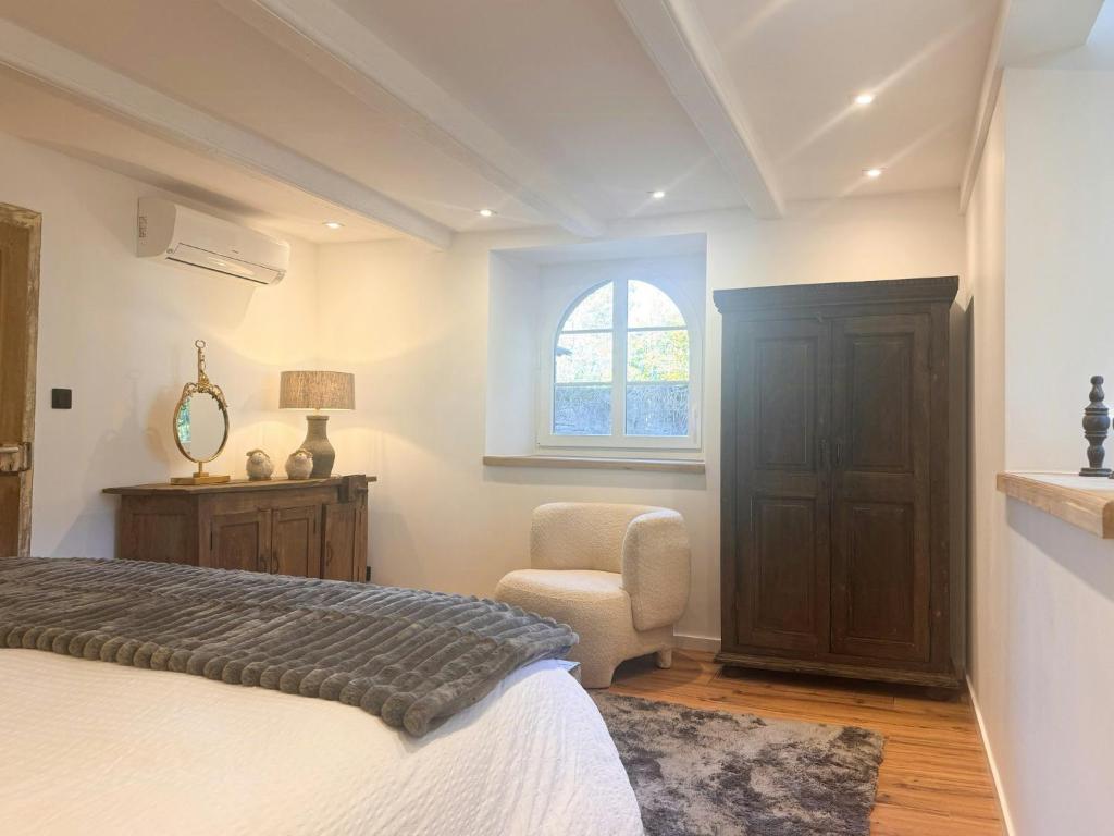 Un dormitorio con una cama y una silla y una ventana. en Charming House Near Gondrexange Lake, en Jeuxey