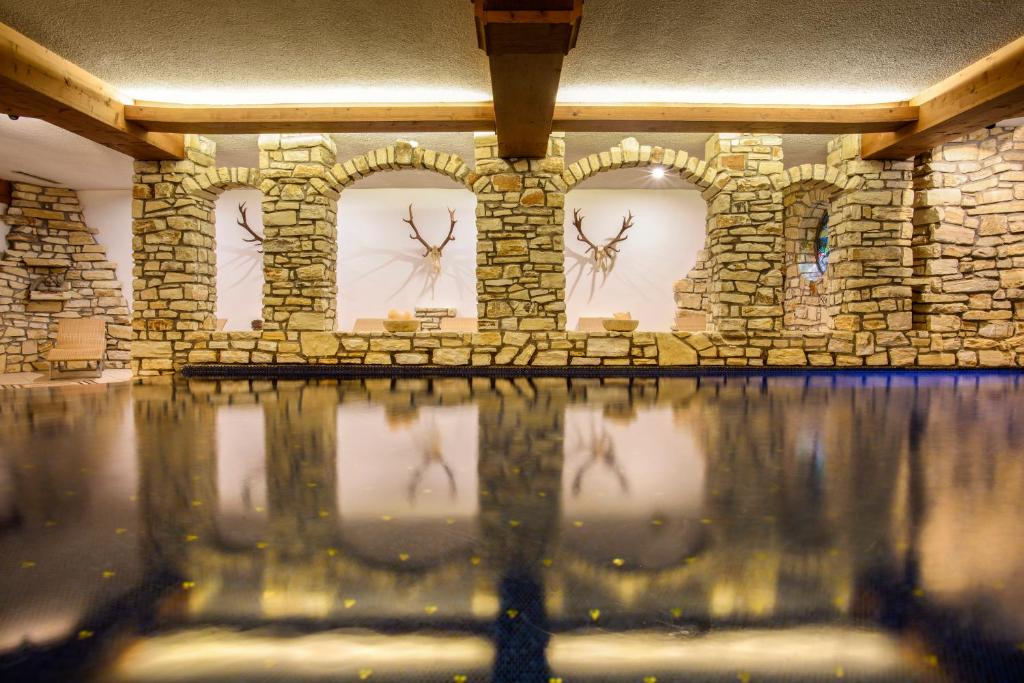 a room with a stone wall with clocks on the wall at Aktiv & Spa Hotel Alpenrose in Schruns-Tschagguns