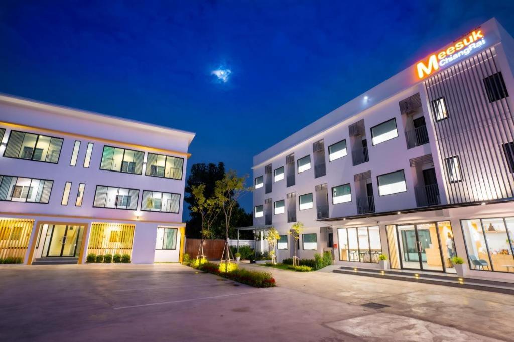 ein großes weißes Gebäude mit einem Schild darauf in der Unterkunft Meesuk ChiangRai Hotel in Chiang Rai