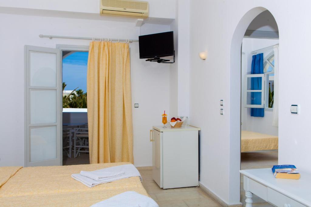 a bedroom with two beds and a tv on the wall at Okeanis Beach in Kamari