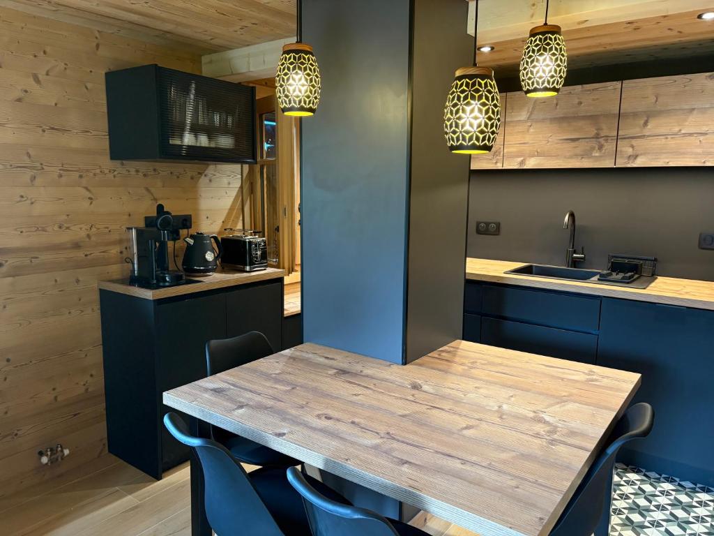 a kitchen with a wooden table and blue cabinets at Appartement neuf dans chalet à Montriond, entre Lac & Ski ! in Montriond