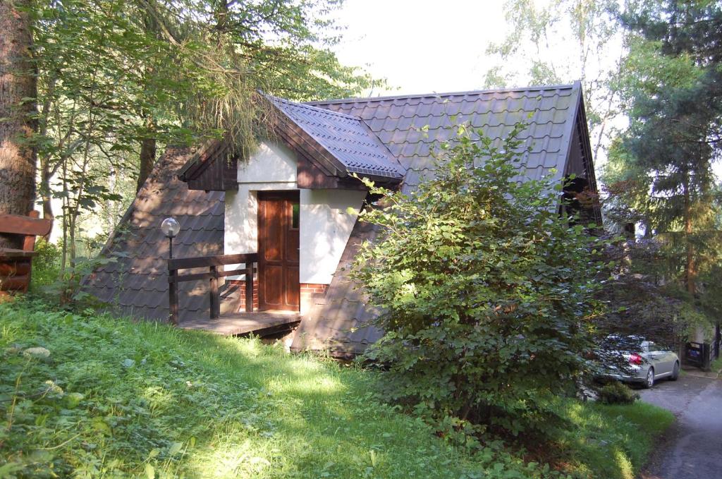 a small house with a wooden door in the grass at Studio Gościnne ANTEK in Czarnów