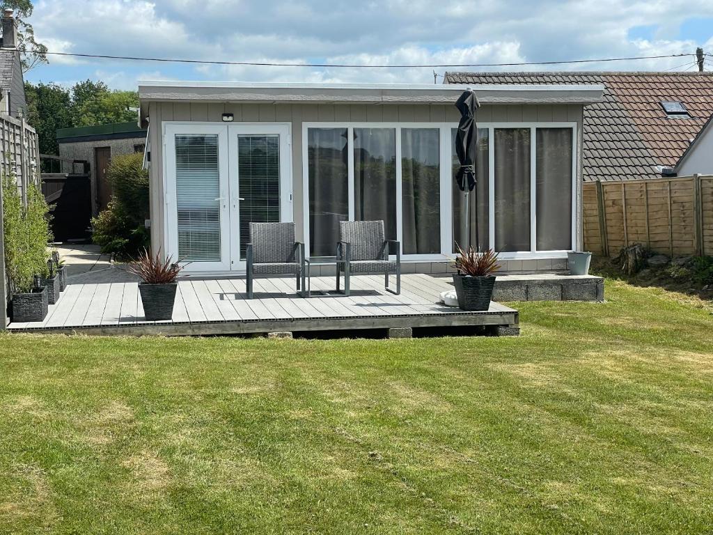 ein Haus mit zwei Stühlen auf einer Holzterrasse in der Unterkunft The Garden Room - A cosy country stay in Cornwall in Callington