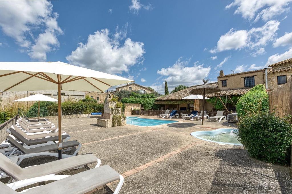 eine Terrasse mit Stühlen und Sonnenschirm und ein Pool in der Unterkunft Casa Rural La Pallissa de Llampaies in Llampaies