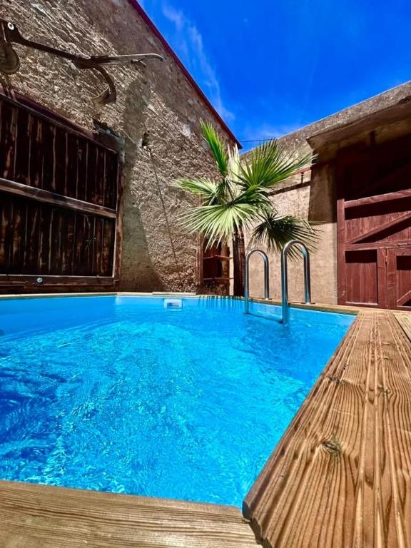 une grande piscine bleue à côté d'un immeuble dans l'établissement La Maison Coloniale Suites privatives de luxe, à Torreilles