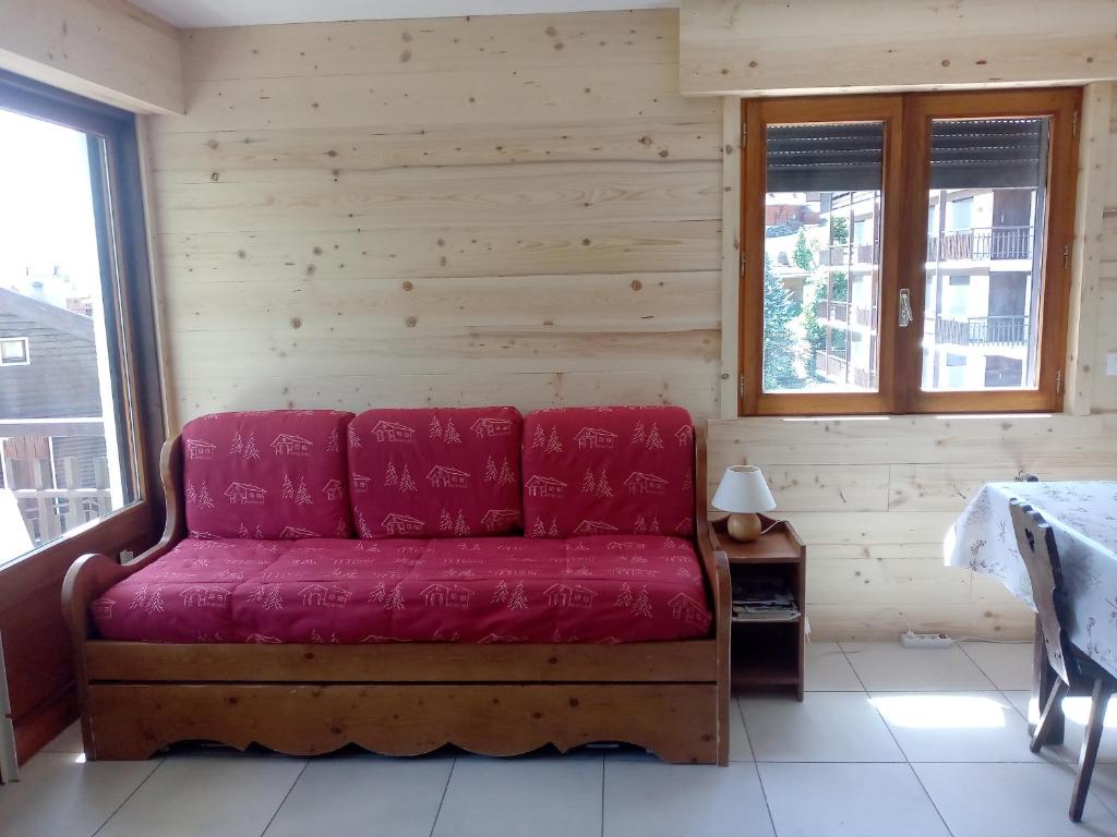 - un canapé rouge dans une chambre dotée de murs en bois dans l'établissement Appartement cosy au Chinaillon, proche commerces et pistes, 4 pers, animaux admis. - FR-1-467-69, au Grand-Bornand
