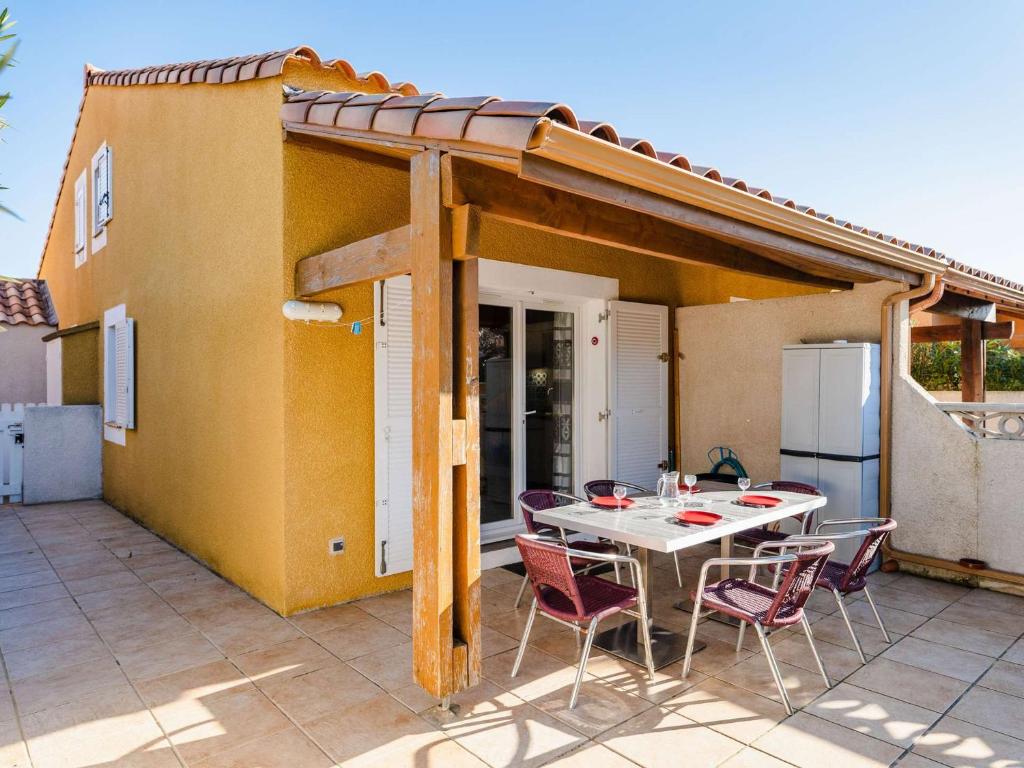 une terrasse avec une table et des chaises ainsi qu'une maison dans l'établissement Pavillon T3 rénové à 400m de la plage avec terrasse, parking et WiFi - Narbonne-Plage - FR-1-409-158, à Narbonne
