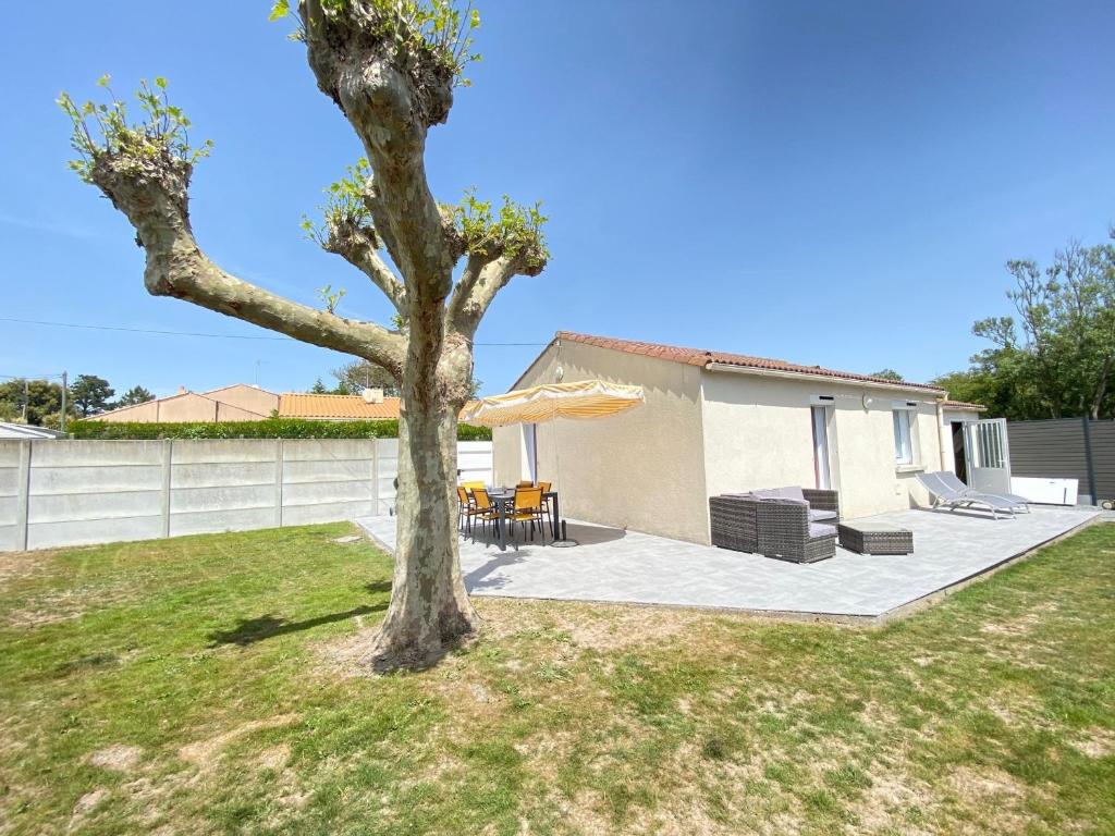 un arbre dans une cour à côté d'une maison dans l'établissement Maison de Charme au Calme avec Jardin Clos, WIFI, Proche Plage du Marais Girard, Animaux Acceptés - FR-1-231-133, à Bretignolles-sur-Mer