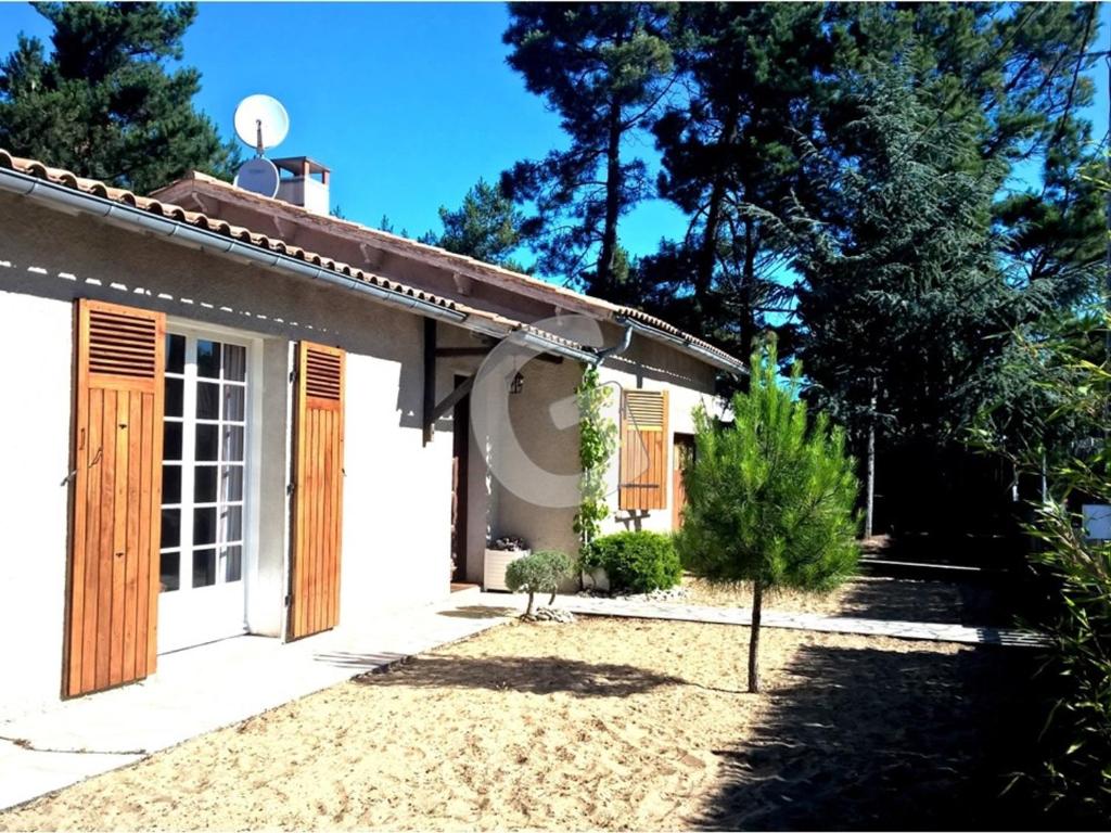 une petite maison blanche avec des portes en bois et une cour dans l'établissement Maison pour 6 avec Wi-Fi, 500m plage, jardin clos, parking - La Tranche-sur-Mer - FR-1-357-78, à La Tranche-sur-Mer