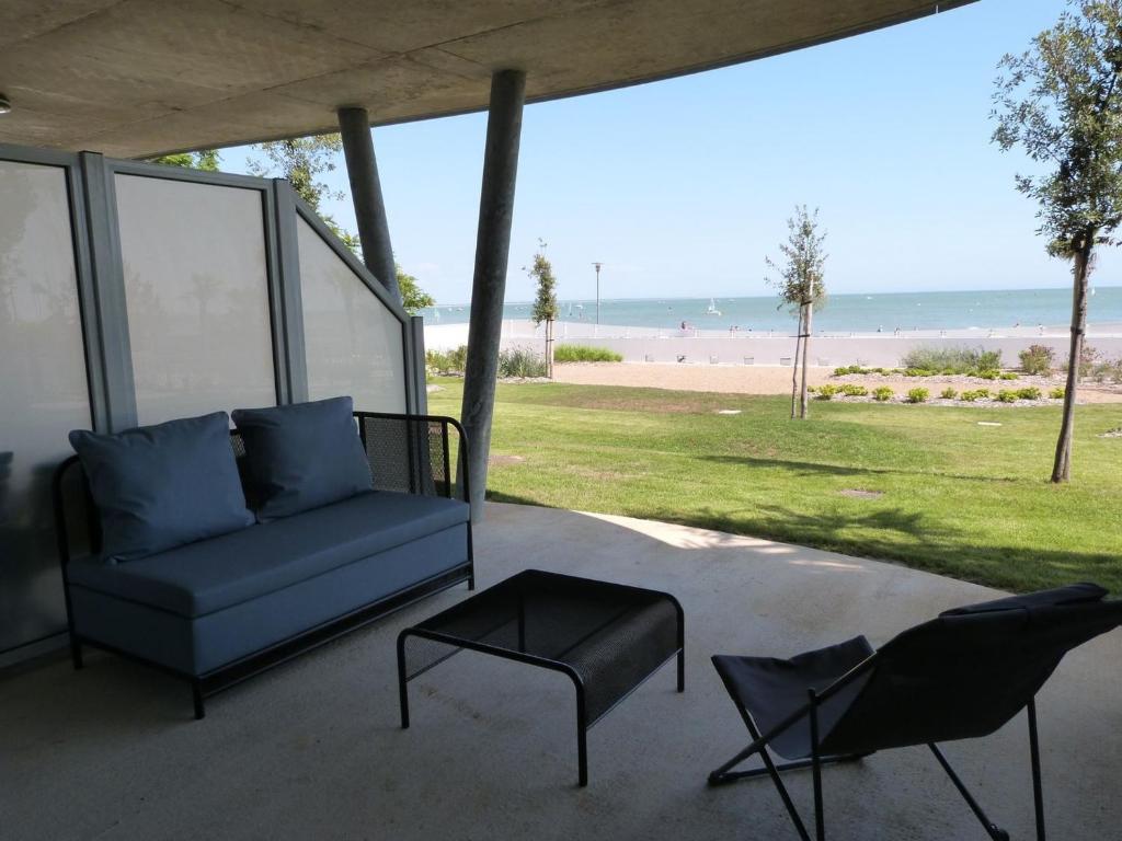 a couch and two chairs on a patio with the beach at Appartement en bord de mer, 2 chambres, piscine, parking, animaux admis - FR-1-194-231 in La Tranche-sur-Mer