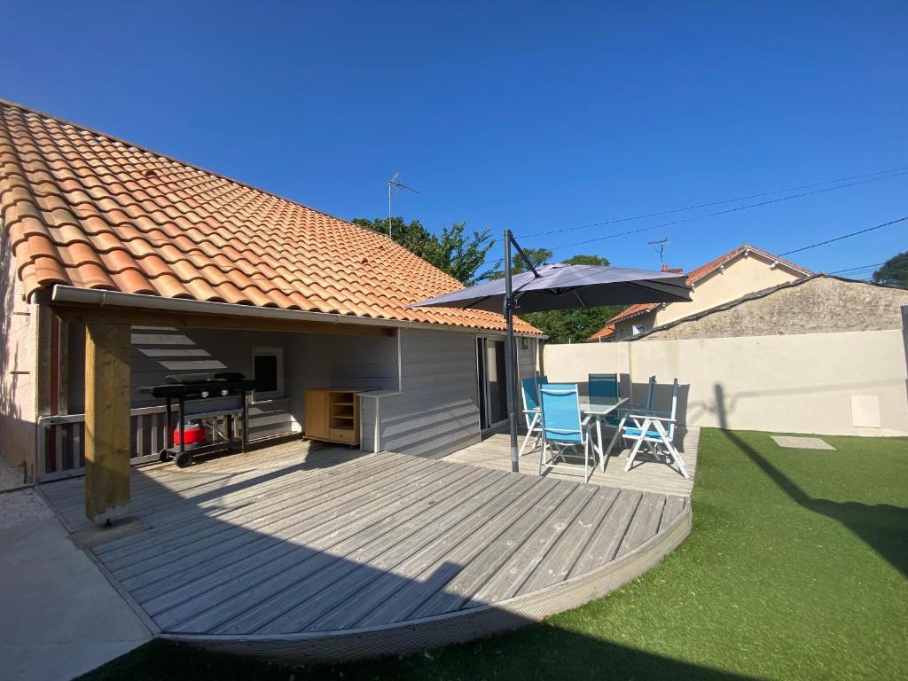 a wooden deck with two chairs and an umbrella at Maison familiale avec terrasse et proche plage à Saint-Brevin-les-Pins - FR-1-364-98 in Saint-Brevin-les-Pins
