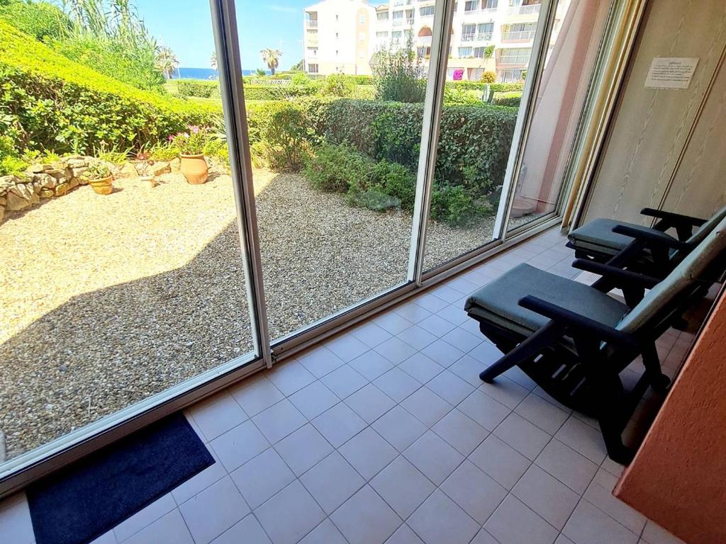 une chambre avec deux chaises et vue sur un patio dans l'établissement T3 climatisé avec piscine, Wi-Fi et parking – À 200 m des plages et commerces - FR-1-316-291, à Six-Fours-les-Plages