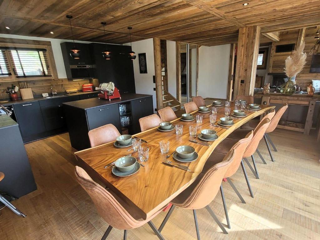 a long wooden table with chairs and a kitchen at Chalet cozy à 4* avec cheminée, WiFi, et balcon proche des pistes aux Gets - FR-1-598-89 in Les Gets