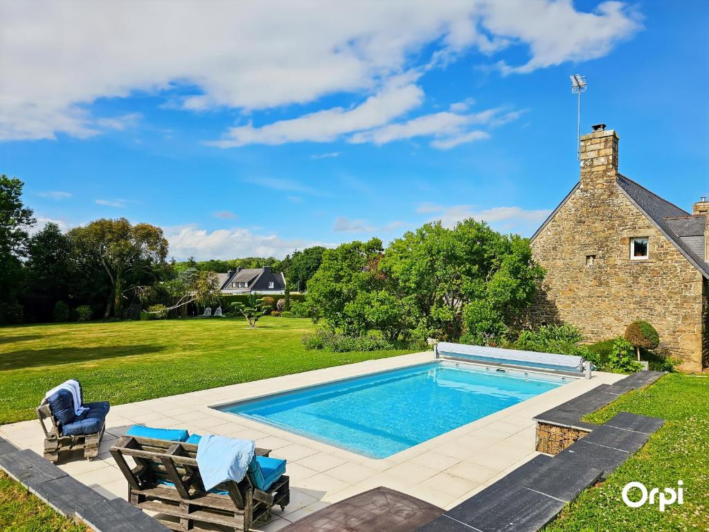 une piscine dans l'arrière-cour d'une maison dans l'établissement Gîte indépendant de charme avec piscine chauffée à Kervignac - 6 couchages, proche plages - FR-1-349-188, à Kervignac