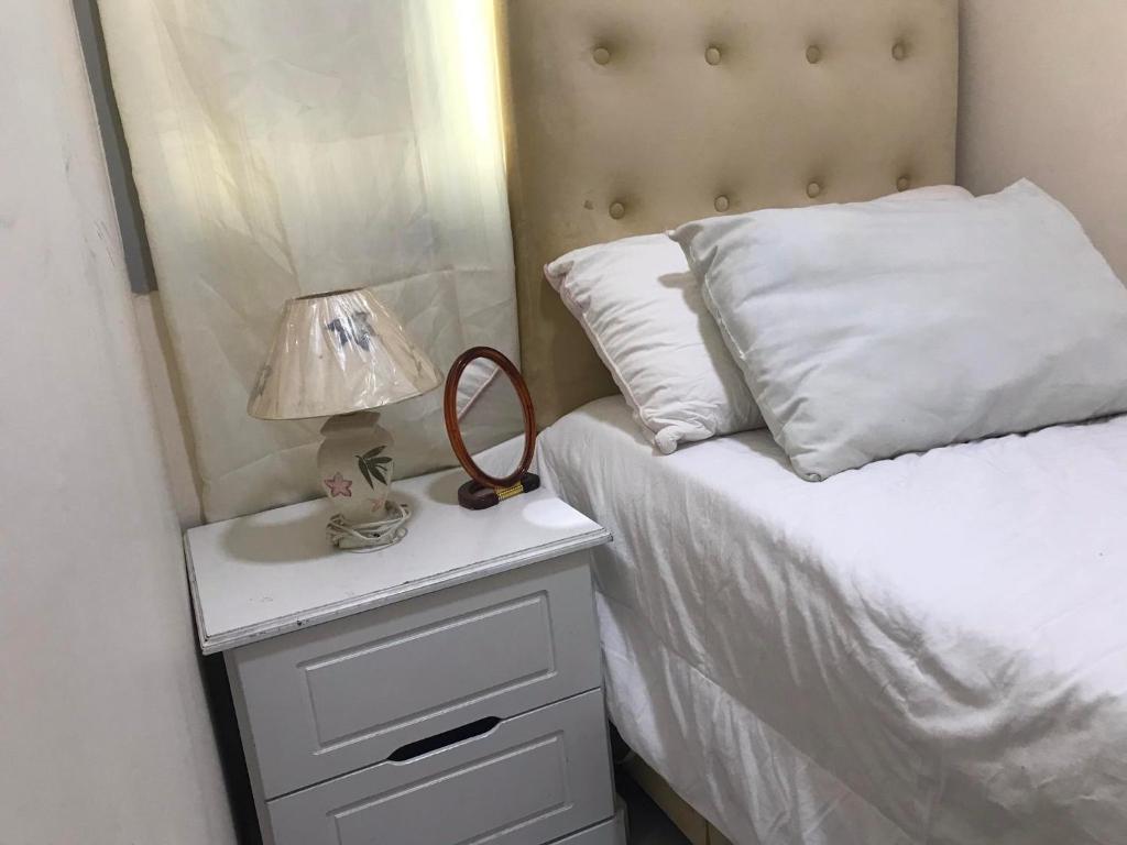 Un dormitorio con una cama y una mesita de noche con una lámpara. en غرفة نوم بالشارقة, en Sabkhah