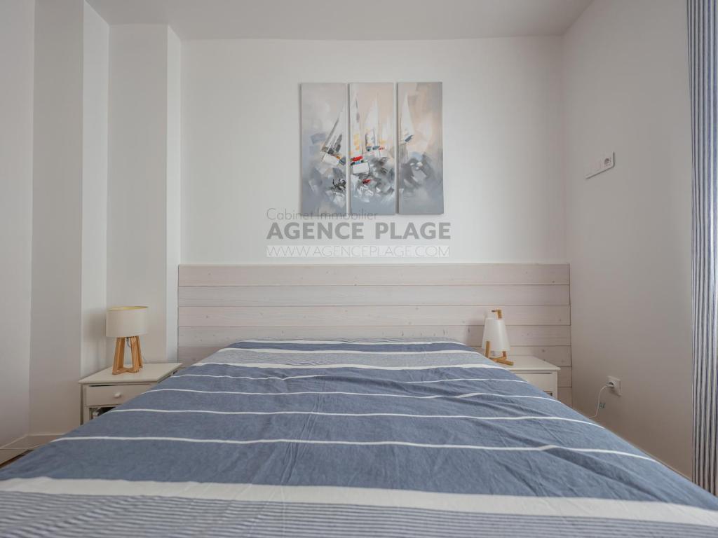- une chambre avec un lit et une couverture rayée bleue dans l'établissement Maison 3 chambres avec jardin et parking à La Chaume, proche plages et commerces - FR-1-197-556, à Les Sables-dʼOlonne