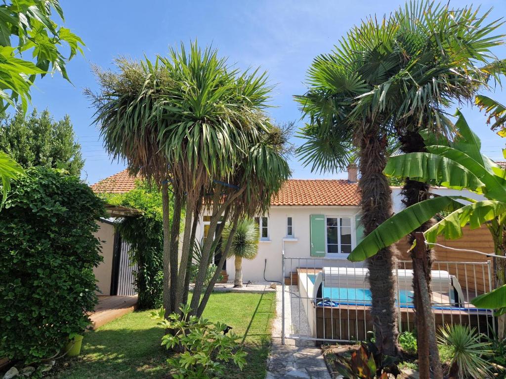 eine Villa mit Palmen und einem Pool in der Unterkunft Maison rénovée avec piscine, jardin clos et terrasse, à 5 min de la plage et des commerces - FR-1-706-5 in Châtelaillon-Plage