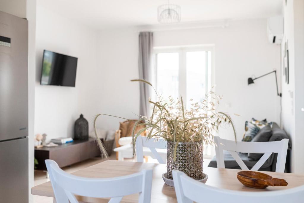 a dining room table with white chairs and a vase with plants at Einalia Holiday Homes near the Beach in (( Elaiónas ))