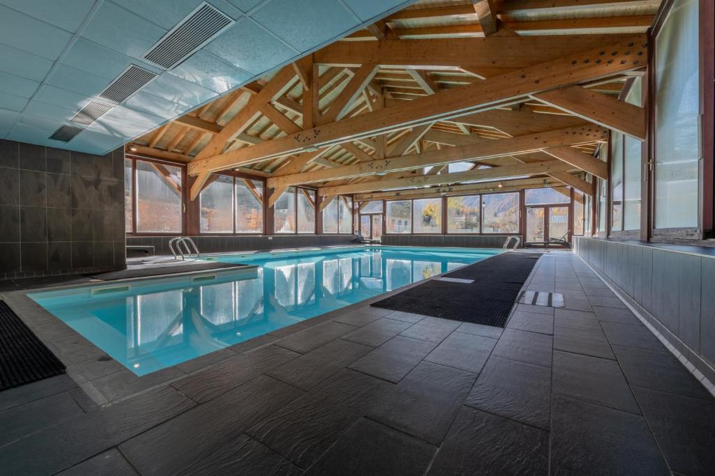 a large swimming pool in a building with wooden ceilings at l'Ours Bleu A35 - Ski in Ski out - Happy Rentals in Vallorcine