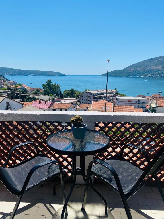 a table and chairs on a balcony with a view of the water at Apartman Igalo Stana in Igalo