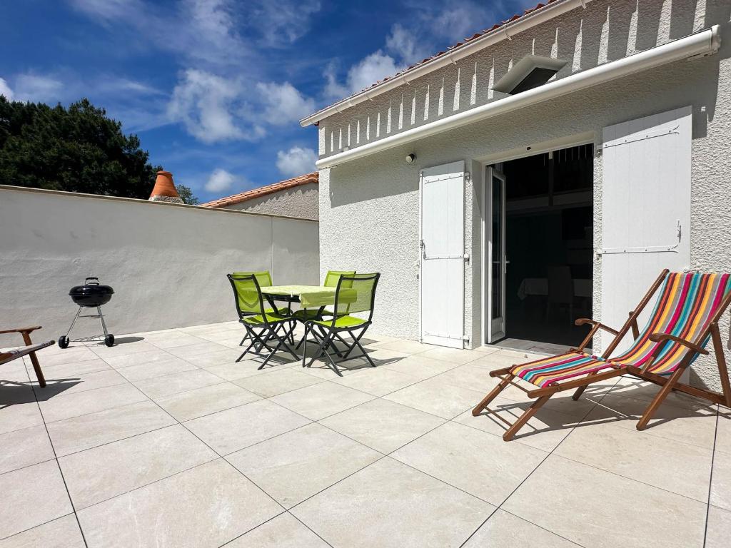 un patio avec des chaises, une table et un grill dans l'établissement Maison 5 Pers à La Palmyre - Terrasse Sud, Plage à 1000m, Commerces à 300m, Calme, WIFI, Parking - FR-1-705-21, à La Palmyre