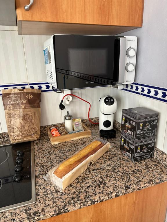 un piano di lavoro della cucina con un microonde e una pagnotta di pane di Casa Rural Hoces del Cabriel a Villargordo del Cabriel