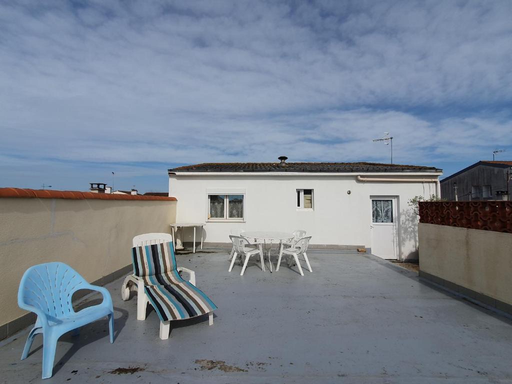 un groupe de chaises et de tables sur une terrasse dans l'établissement Appartement avec Terrasse, 2 Chambres, Centre, Plage à Proximité, Animaux sur Demande - FR-1-476-207, à LʼAiguillon-sur-Mer