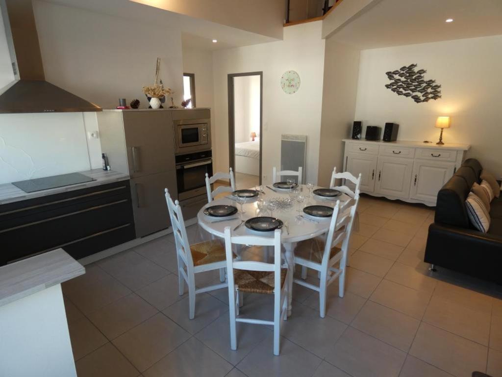 une cuisine et une salle à manger avec une table et des chaises blanches dans l'établissement Appartement moderne 68m² à Notre-Dame-de-Monts, 6 pers, accès PMR, terrasse, proche forêt et plages - FR-1-540-277, à Notre-Dame-de-Monts