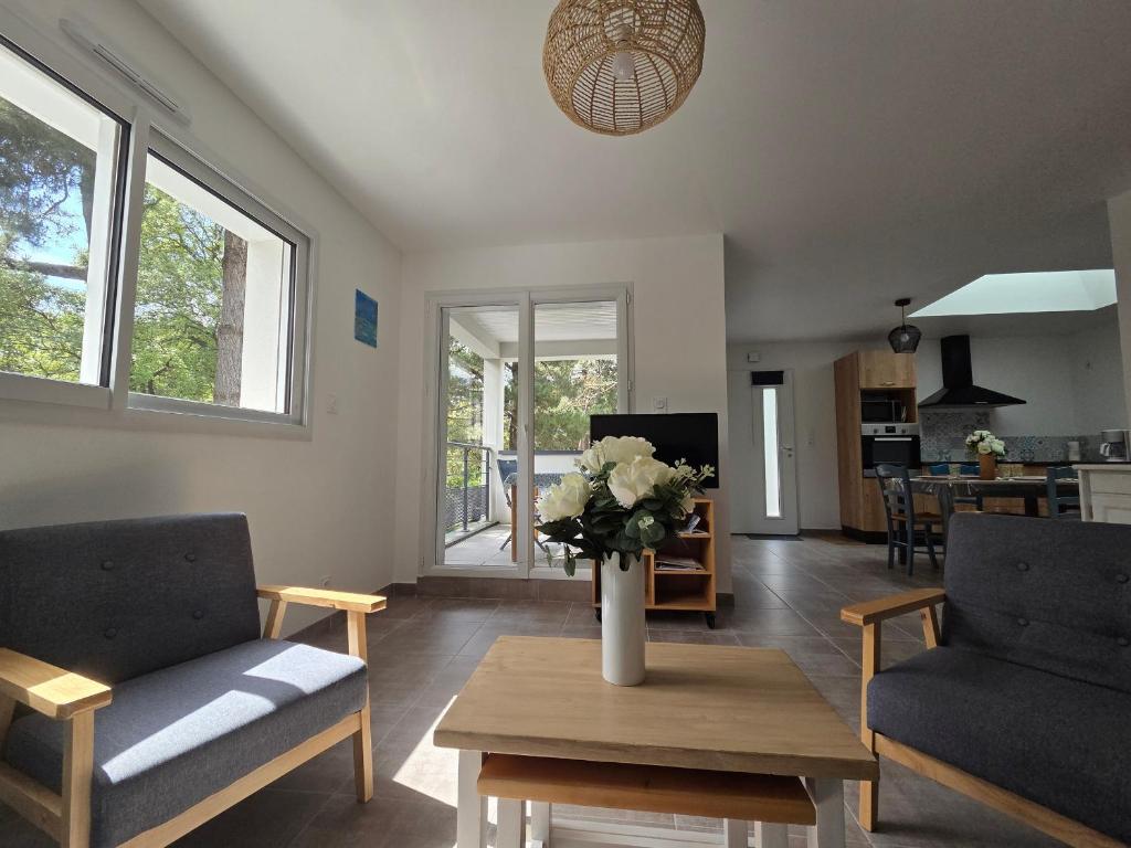 un salon avec un vase de fleurs sur une table dans l'établissement Appartement neuf 62 m², 5 couchages, à 250 m de la plage - balcon, jardin privé, et parking inclus - FR-1-364-111, à Saint-Brévin-les-Pins