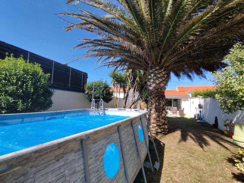 un palmier dans une cour avec une piscine dans l'établissement Séjour de rêve à Saint-Denis d'Oléron : Maison 10 pers, piscine, proche phare de Chassiron - FR-1-778-4, à Saint-Denis-dʼOléron