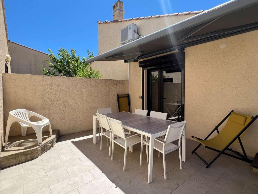 un patio avec une table et des chaises sur un patio dans l'établissement Maison clim. proche mer, terrasse et parking privatisé, 6 pers. - FR-1-307-230, au Grau-du-Roi