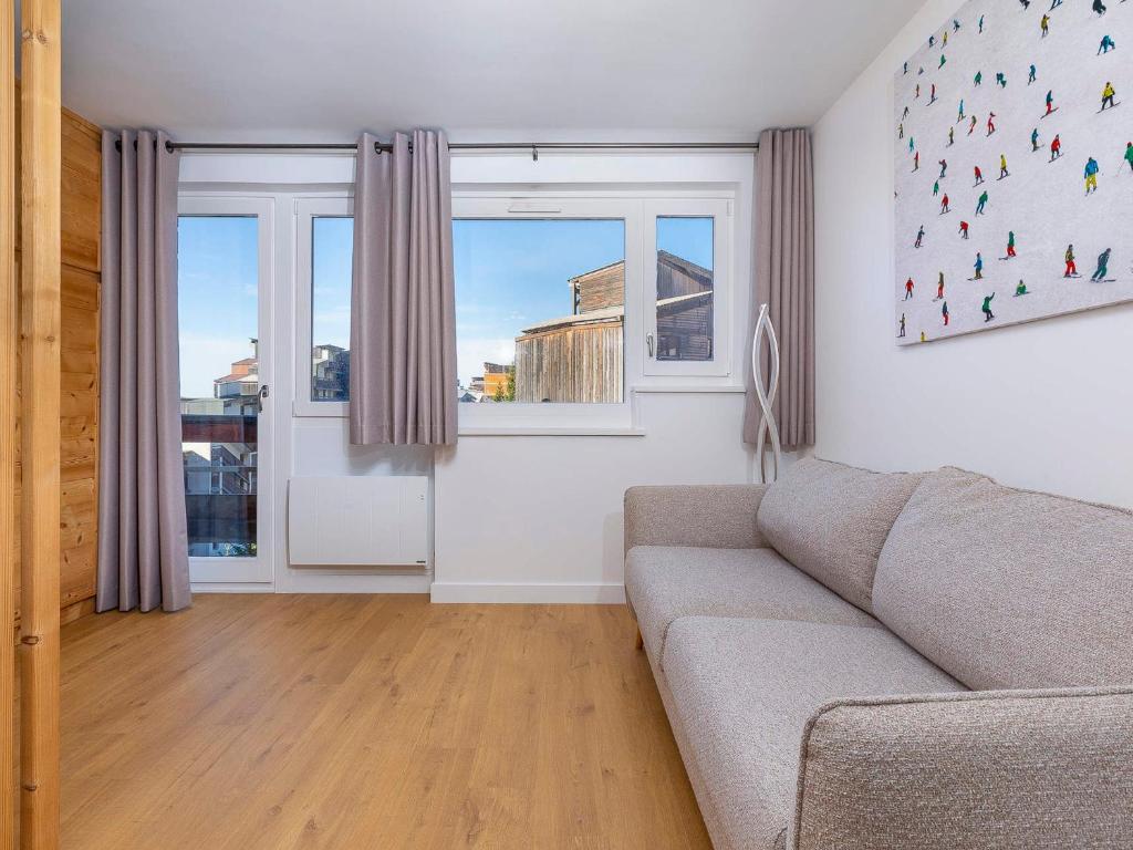 un salon avec un canapé et deux fenêtres dans l'établissement Charmant 2 pièces rénové, internet fibre, balcon, casier à ski, quartier paisible - FR-1-314-210, à Morzine