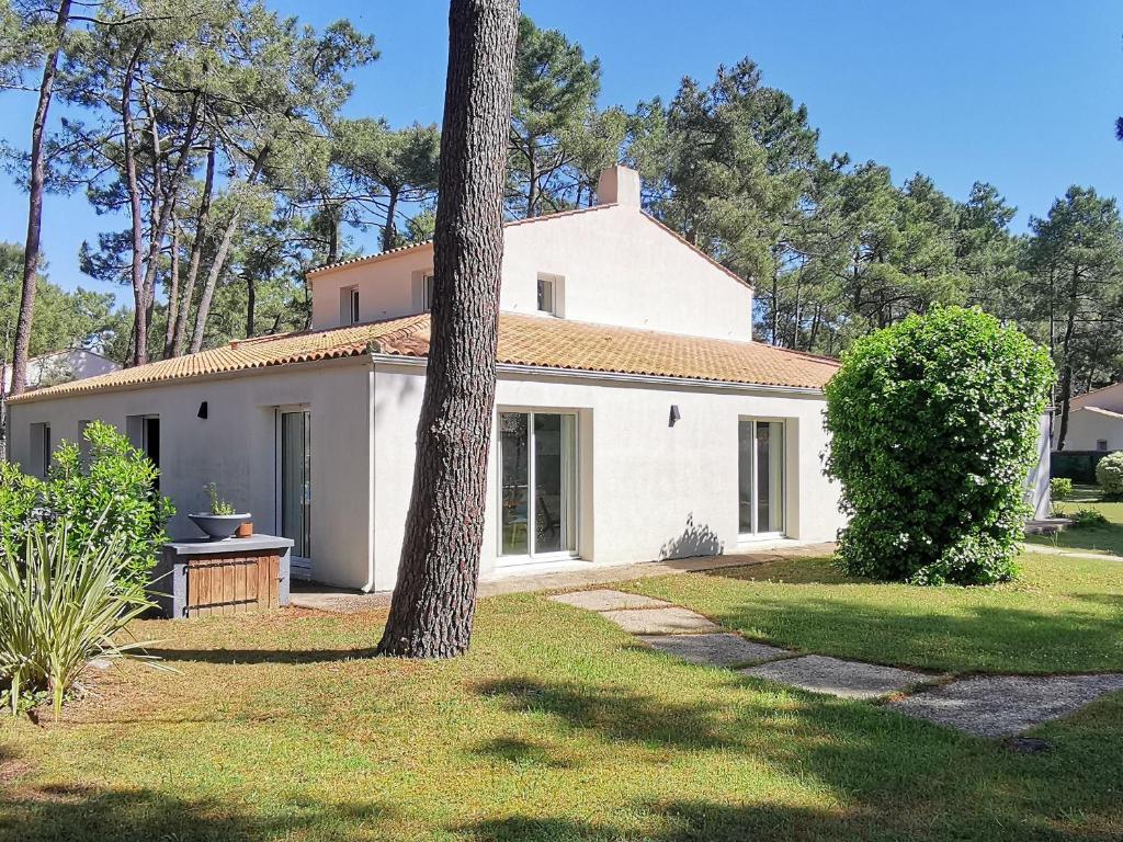 une maison blanche avec un arbre dans la cour dans l'établissement Villa Résidentielle 5 Chambres Proche Plage, WiFi, Parking - FR-1-194-225, à La Faute-sur-Mer
