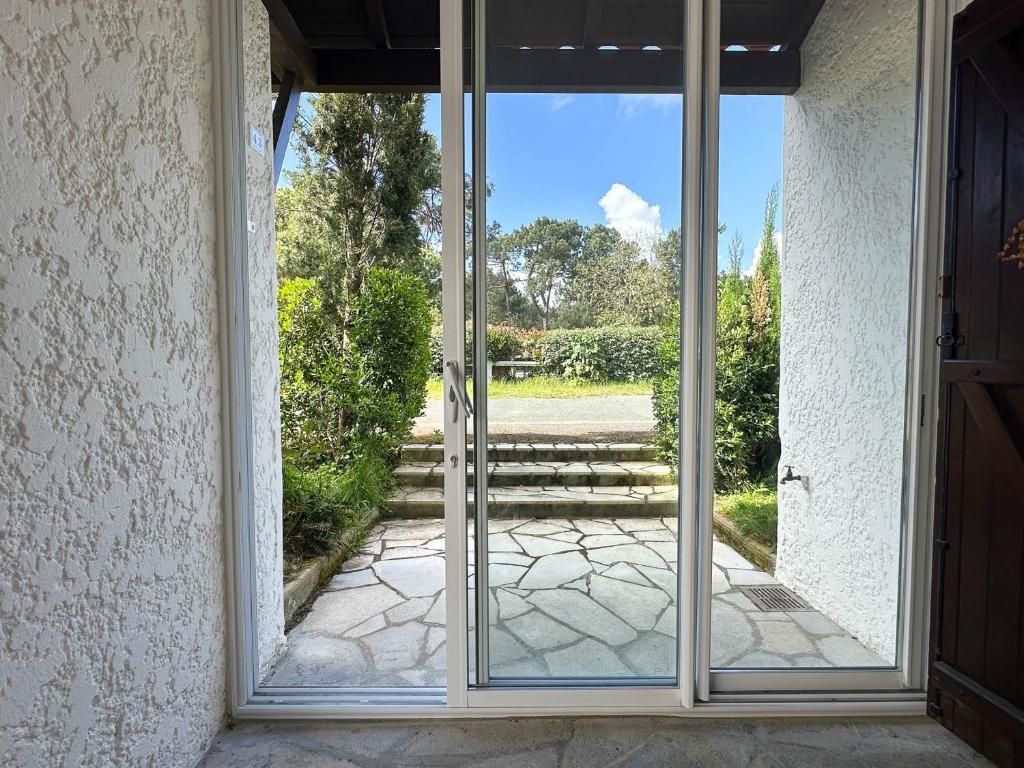 une porte en verre ouverte avec vue sur la cour dans l'établissement Villa 4 Pièces Proche Plage avec Parking à La Palmyre - FR-1-705-31, aux Mathes