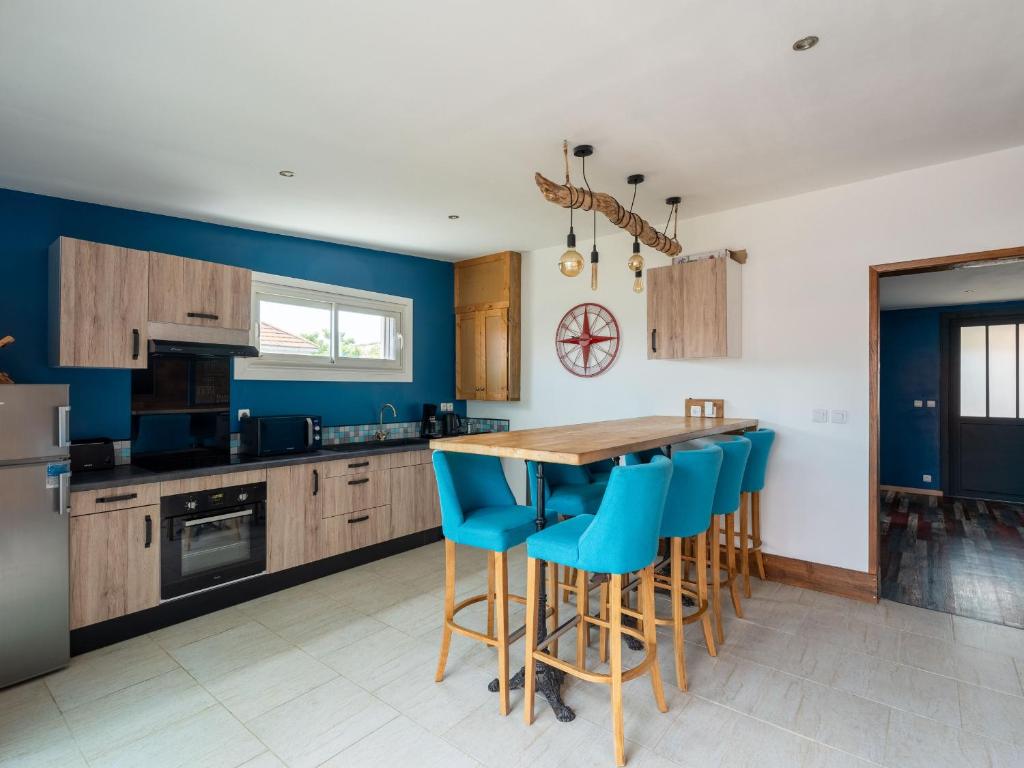 une cuisine avec une table en bois et des chaises bleues dans l'établissement Maison Rénovée 6p, à 150m Plage, Terrasse, BBQ, Parking, Ménage Inclus - FR-1-50-121, à Mimizan