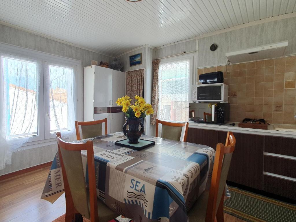 une cuisine avec une table avec un vase de fleurs dessus dans l'établissement Charmant Studio à La Faute-sur-Mer, proche plages et commerces, idéal pour 2 pers. - FR-1-476-210, à La Faute-sur-Mer