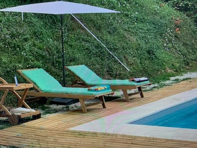 - deux chaises longues et un parasol à côté de la piscine dans l'établissement Maison, vue et piscine privée avec ouverture septembre à côté de Sarlat, à Bézenac