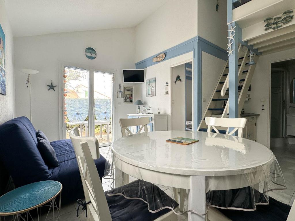 un salon avec une table et des chaises blanches dans l'établissement Maison 4 pers avec piscine, tennis, proche plages et port - La Palmyre - FR-1-705-57, aux Mathes