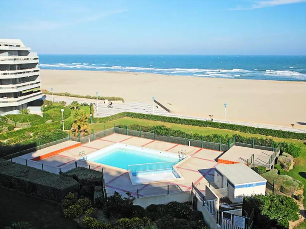 - une piscine à côté d'une plage avec un bâtiment dans l'établissement Appartement 2 pièces avec piscine et parking, accès direct plage - FR-1-748-27, à Canet