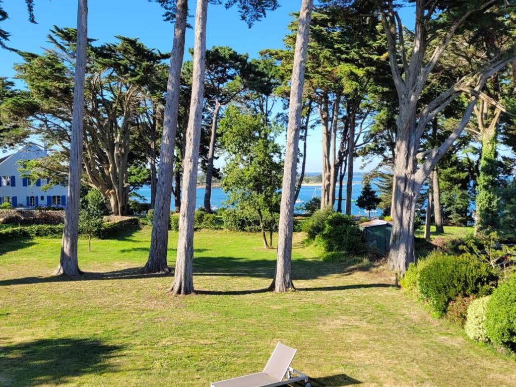 une chaise blanche assise dans un parc arboré dans l'établissement Maison calme 8-9 pers, 4 ch, jardin près du Logeo - FR-1-639-95, à Sarzeau