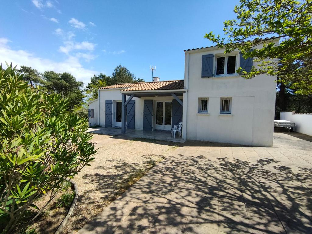 une maison blanche avec un patio et une cour dans l'établissement Villa au Calme avec Jardin, Proche Plage, Équipée pour Familles - FR-1-194-285, à La Faute-sur-Mer