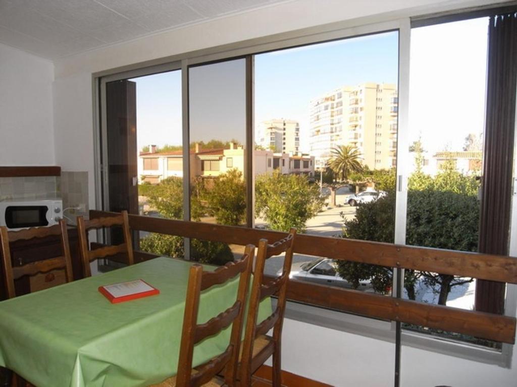 une salle à manger avec une table et une grande fenêtre dans l'établissement Appartement 2 pièces avec piscine, tennis et parking, animaux permis, à 500m de la mer - FR-1-776-121, à Argelès-sur-Mer