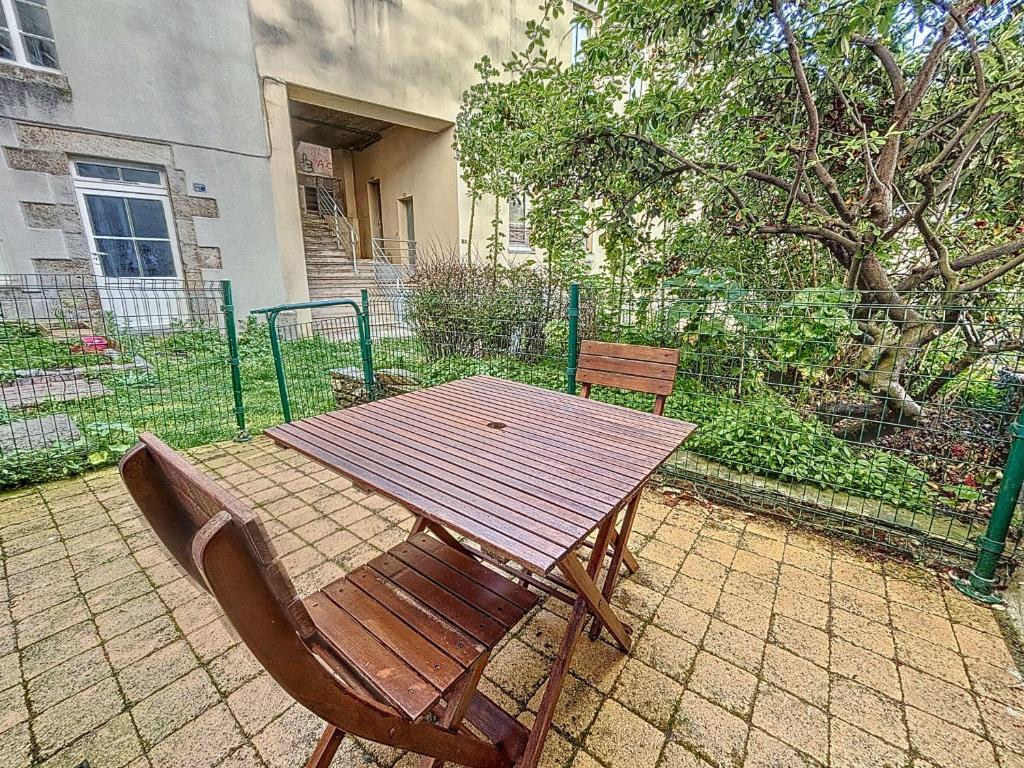 une table et des chaises en bois assises sur une terrasse dans l'établissement Charmant studio refait à neuf avec terrasse - animaux admis, Wi-Fi gratuit - FR-1-361-562, à Granville