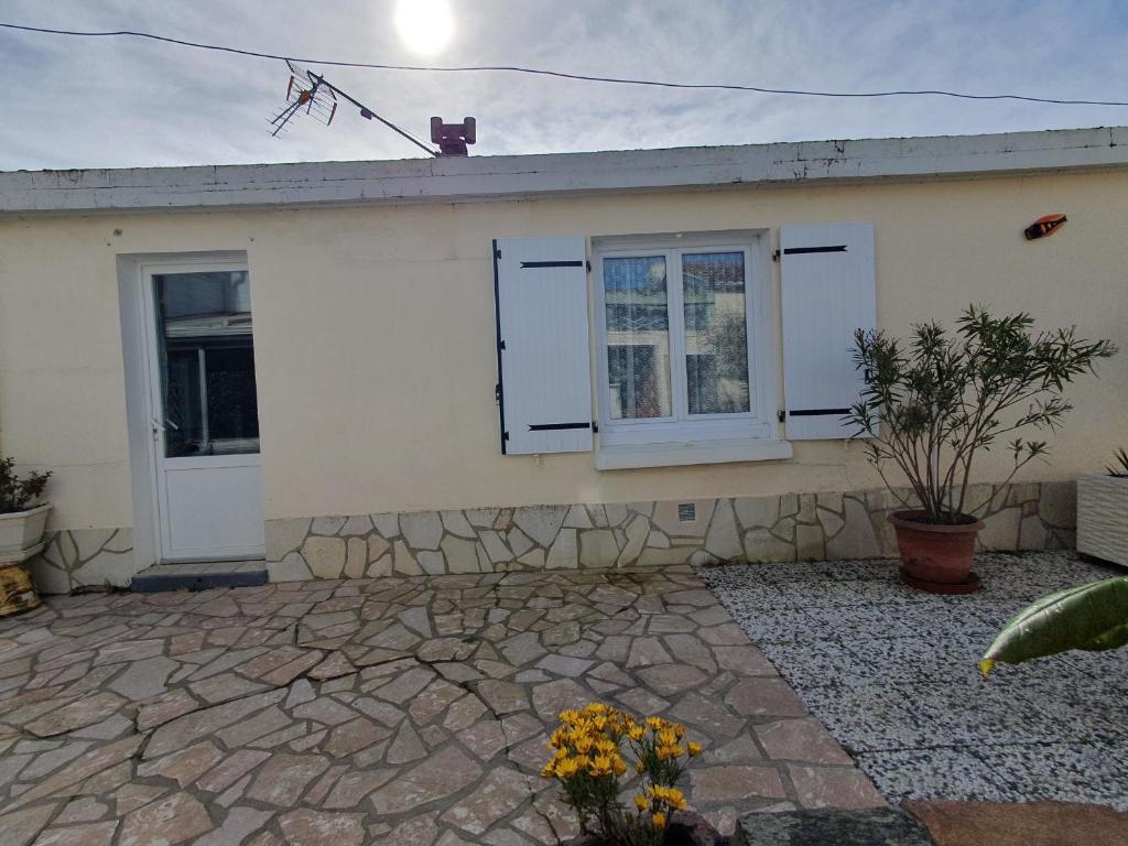 Cette maison blanche dispose de 2 fenêtres et d'une terrasse. dans l'établissement Appartement RDC Centre Aiguillon-sur-Mer, Proche Marché, Plages et Commerces, 4 Pers, Animaux Ok - FR-1-476-209, à LʼAiguillon-sur-Mer