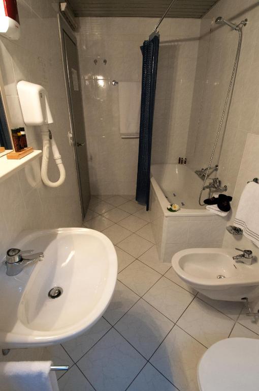 a bathroom with a sink and a tub and a toilet at Hotel Bahnhof Haus in Chiasso