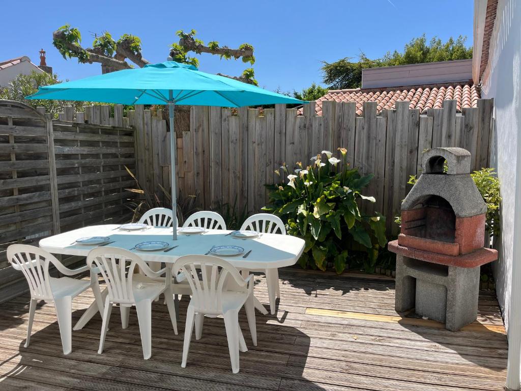 une table et des chaises avec un parasol et une cuisinière dans l'établissement Maison mitoyenne proche plage, centre Barbâtre, pour 4 personnes - FR-1-823-109, à Barbâtre