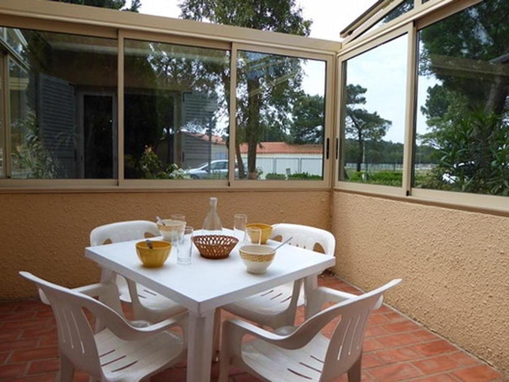une table et des chaises blanches sur une terrasse avec fenêtres dans l'établissement Appartement 2 pièces, 4 pers, proche plage et commerces, parking, animaux admis - FR-1-776-115, à Argelès-sur-Mer