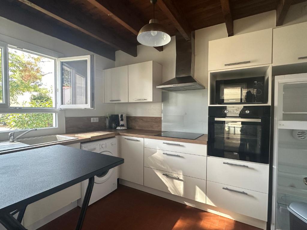 une cuisine avec des armoires blanches et un comptoir noir dans l'établissement Villa 4 chambres La Palmyre avec Patio et WIFI - FR-1-705-96, aux Mathes
