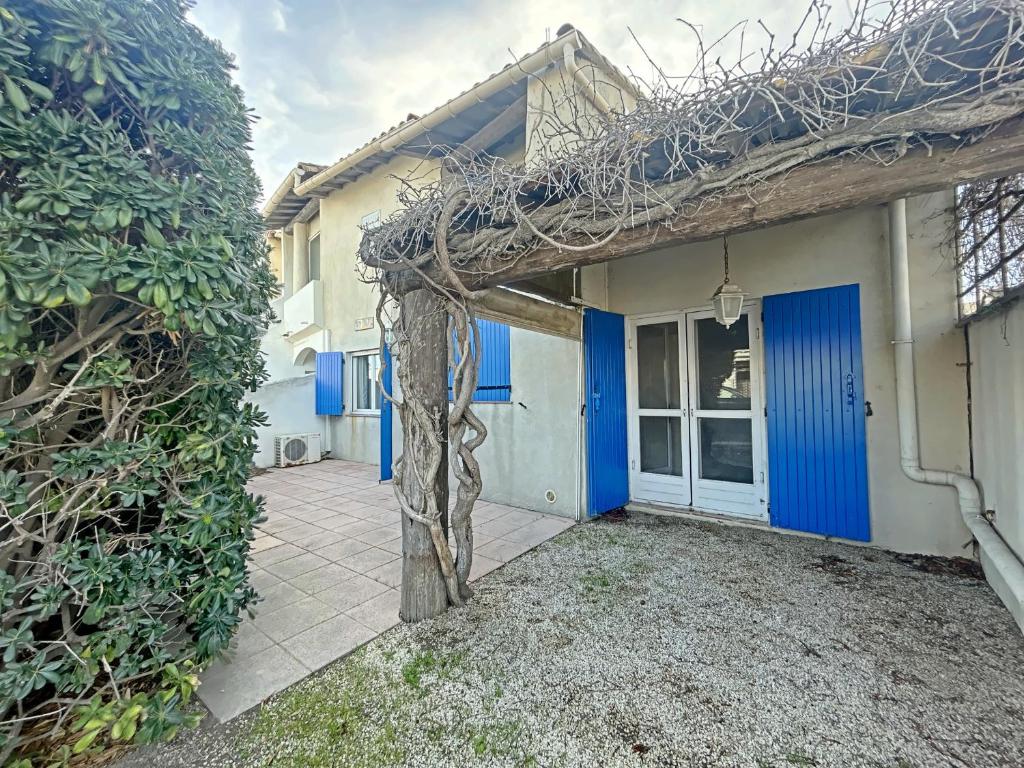 une maison avec des portes bleues et une clôture dans l'établissement Appartement 6 pers. aux Saintes-Maries-de-la-Mer - FR-1-475-223, à Saintes-Maries-de-la-Mer