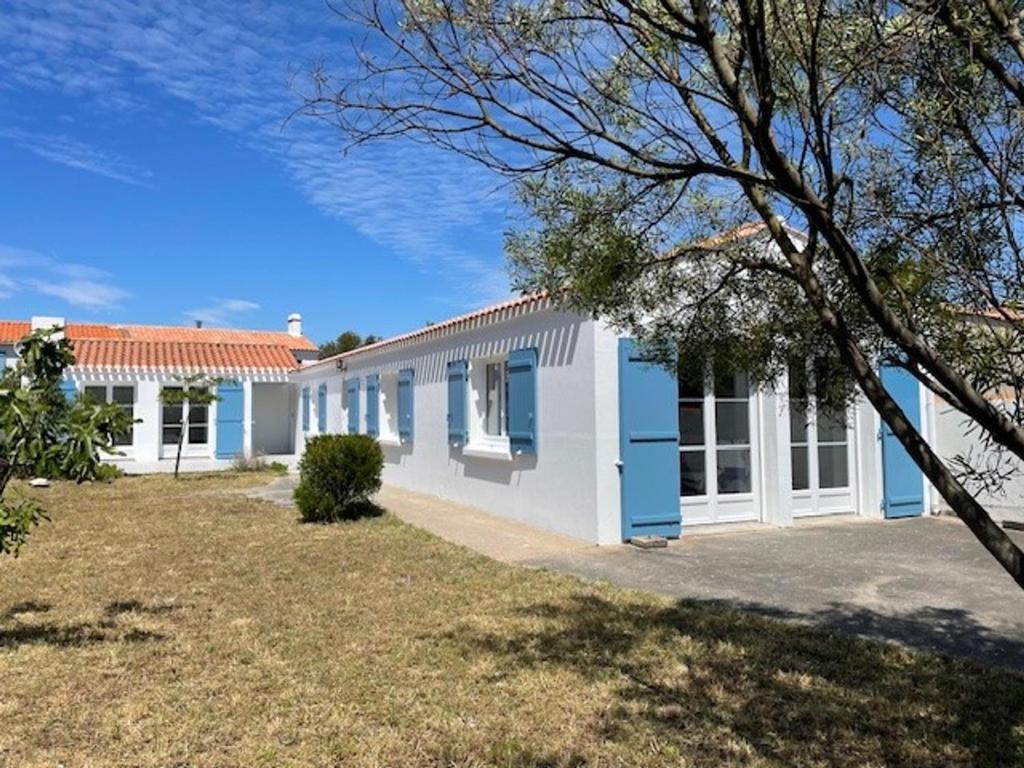 une maison blanche et bleue avec une cour dans l'établissement Maison de vacances à l'Épine - 4 personnes - Près de la plage - FR-1-823-45, à LʼÉpine